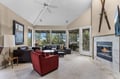 Unwind in your spacious living room with cozy fireplace, comfortable seating, and panoramic tree views through floor-to-ceiling windows.