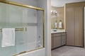 Main floor Primary Bathroom. Refresh in your spacious bathroom with gleaming fixtures, elegant gold accents, and plush towels waiting for your arrival.
