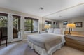 Main Floor Primary King Bed Wake up in your serene bedroom with warm lighting and French doors opening to your private balcony overlooking lush greenery.