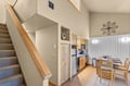 Your open-plan retreat features a fully equipped kitchen with sleek appliances, a cozy dining nook for meals together, and soaring vaulted ceilings that create a bright, airy welcome.