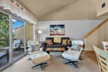 Settle into your spacious living room, where iconic lounge chairs and a plush sofa invite you to relax. Step through the glass doors to your private balcony, surrounded by trees and fresh mountain air.