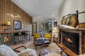 Sink into the plush loveseat by your crackling fireplace, where warm wood accents, vaulted ceilings, and golden lighting create your perfect mountain retreat.
