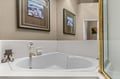 Upstairs Primary Suite, King with Ensuite Bathroom. Sink into your private soaking tub surrounded by elegant artwork and warm lighting for the perfect evening unwind.